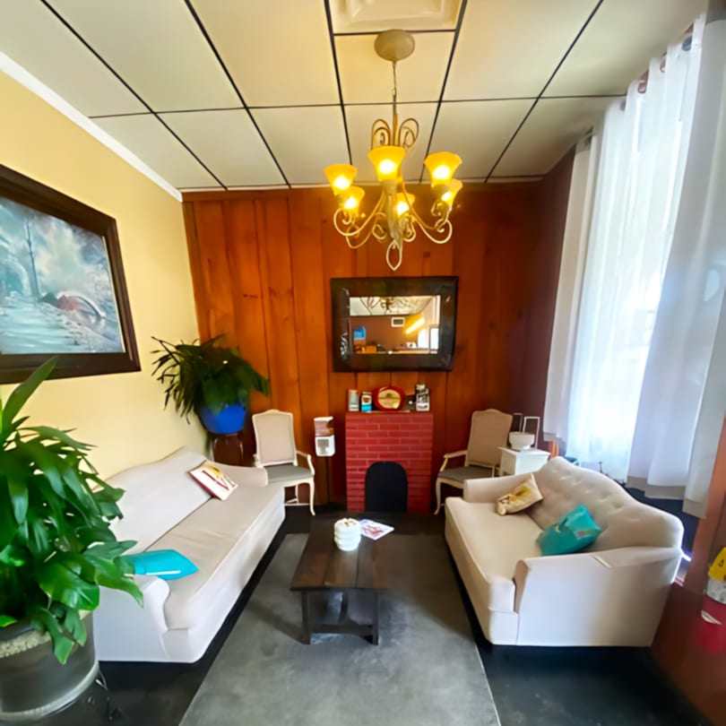 Cozy waiting area with two cream sofas, a coffee table, and a red brick fireplace.