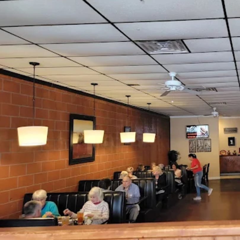 Ishy's Grill dining room with patrons seated in booths, a server walking, and brick walls.
